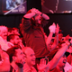 A League of Legends fan stands up in a crowd and holds their head in disbelief.